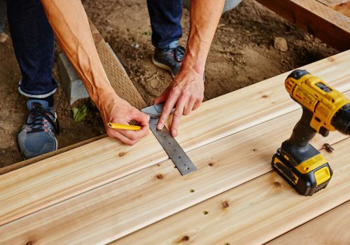 man drilling and measuring wood for deck man drilling and measuring wood for deck