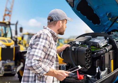 Man using digital tablet to inspect tractor engine with modern m Man using digital tablet to inspect tractor engine with modern m
